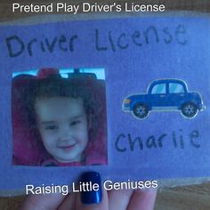 a child's hand holding up a photo with a blue car and name tag on it