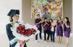 a group of women in graduation gowns standing next to each other and holding flowers