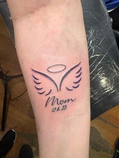 a woman's arm with a tattoo on it that reads mom 2013 and an angel wing