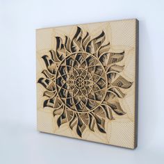 a wood carved artwork depicting a sunflower on a white background with black lines in the center