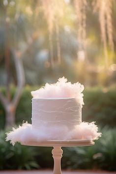 a white wedding cake with fluffy pink icing