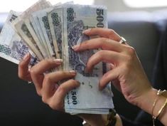 a woman holding out her hands with money in front of her face