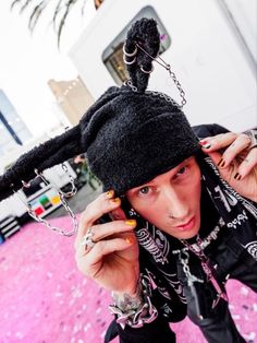 a woman with piercings and a black hat on her head is holding onto a chain