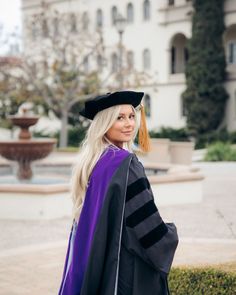 a woman in a graduation gown and cap is posing for the camera with her hand on her hip