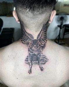 the back of a man's neck with an owl tattoo on his upper part