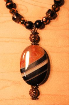 My husband and I designed and handmade this lovely one-of-a-kind beaded necklace.  The beads are semi-precious gemstone, crystal, and copper tone metallic, and the pendant is a beautiful orange, black, and cream agate.  And, the pendant is reversible - the reverse side is black and cream.   This necklace measures 22 inches in length, and the agate pendant measures an additional 2.5 inches.  It has a toggle clasp. Ours is a non-smoking home. Handmade Beaded Necklace, Agate Pendant Necklace, Handmade Beaded Necklaces, Long Beaded Necklace, Black And Orange, Agate Pendant, Toggle Clasp, Etsy Jewelry, Necklace Handmade