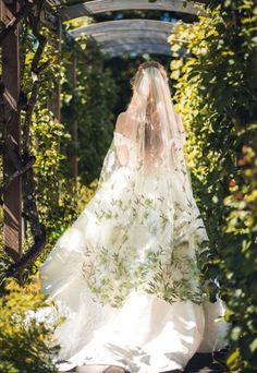 a woman in a wedding dress walking down a path