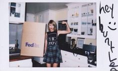 a woman standing in a kitchen holding a box