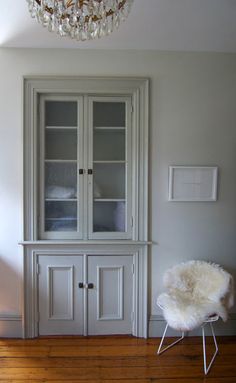 a white china cabinet sitting in the corner of a room next to a chandelier