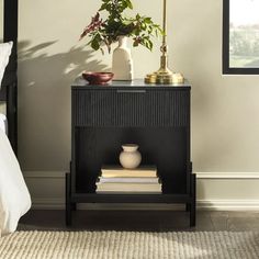 a nightstand with books and a vase on it