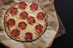 a pepperoni pizza sitting on top of a piece of wax paper