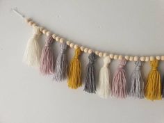 the tasselled garland is hanging from a string with wooden beads and multicolored tassels