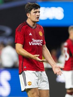 a man standing on top of a soccer field wearing a red shirt and white shorts