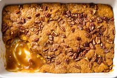 a close up of a cake in a pan with pecans on top and caramel sauce