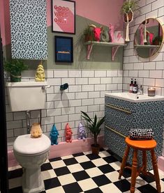 a bathroom with black and white checkered flooring, pink walls and shelves above the toilet