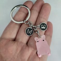 a hand holding a keychain with a pink pig on it's side