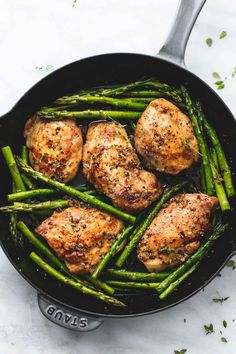 chicken and asparagus in a skillet with a serving spoon on the side