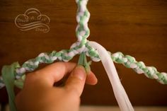 someone is tying a piece of green and white string