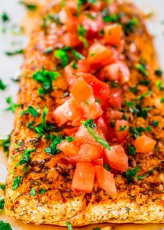 a piece of fish with tomatoes and parsley on it