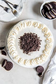 an oreo cookie cake with white frosting and chocolate chips on the plate next to it