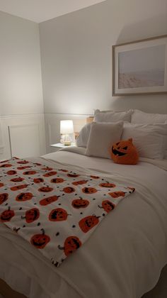 a bed with white sheets and orange pumpkins on it