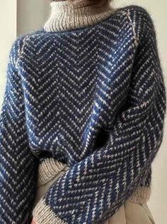 a woman wearing a blue and white knitted sweater with an over sized turtle neck