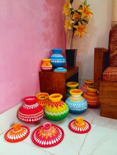 brightly colored vases are sitting on the floor in front of a pink wall