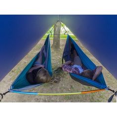 two people laying in hammocks on the ground