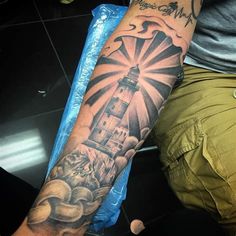 a man with a lighthouse tattoo on his arm