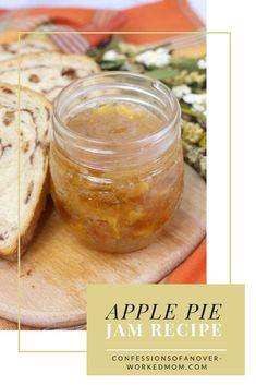 an apple pie jam in a jar on a cutting board next to some slices of bread