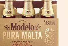 four bottles of modelo pura malta are sitting in a cardboard box on a table