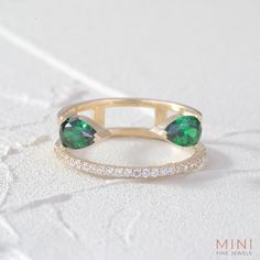 an emerald colored ring with two diamonds on the bottom and one green stone in the middle