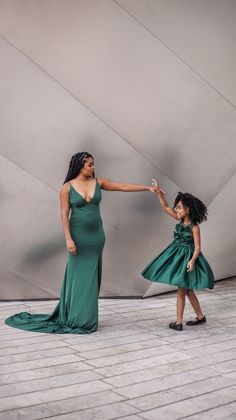 a mother and daughter holding hands in front of a building with a large sculpture behind them