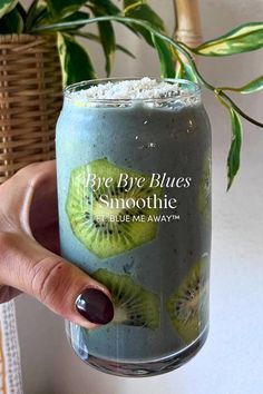 a person holding up a glass with some fruit on it and the words bye bye blues smoothie