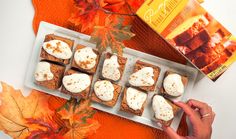 there are many small pieces of food on the table next to some leaves and a box of pumpkins