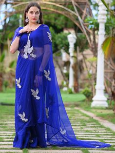 This is a three-piece midnight blue bird saree set from the Ensembles collection. The midnight blue bird saree is paired with a midnight blue blouse. There is beautiful bird motifs of shimmer cutdana work all over the saree. This saree set is crafted in semi pure organza fabric. The outfit is completed with a heavily embellished, cutdana work shimmer bird shape handbag. Blue Floor-length Party Wear Saree, Blue Pre-draped Saree With Zari Work For Evening, Traditional Blue Pre-draped Saree For Evening, Evening Blue Pre-draped Saree With Zari Work, Evening Party Wear Saree Palazzo Set, Blue Pre-draped Saree For Festive Party Wear, Blue Party Wear Saree With Zari Work, Blue Georgette Evening Sets, Blue Zari Work Party Wear Pre-draped Saree