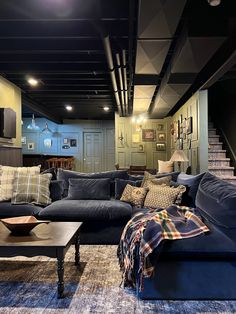 a living room filled with lots of furniture next to a stair case on the wall