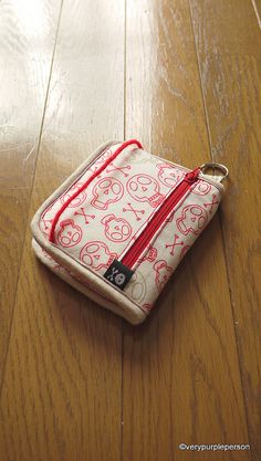 a small purse sitting on top of a wooden floor next to a red zippered bag