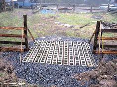 a metal grate sitting on top of a pile of gravel next to a fence