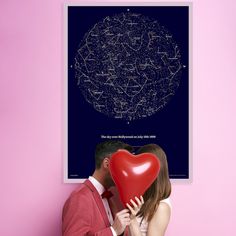 a man and woman kissing in front of a poster with stars on the night sky