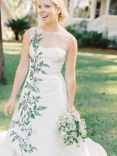 a woman in a wedding dress holding a bouquet smiles at the camera while standing outside