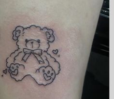 a small teddy bear tattoo on the side of a woman's thigh with hearts