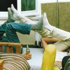 four people laying on the floor with their feet up and one person holding a beer