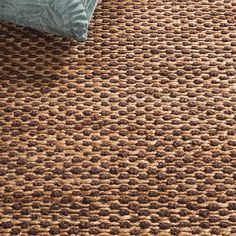 an area rug with brown and blue colors on the floor in front of a bed