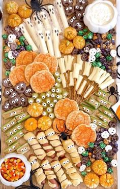 an assortment of halloween treats are arranged on a wooden board with candy and candies