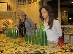 two women standing at a counter with green cups