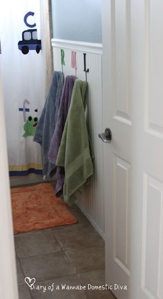 a bathroom with towels hanging on the wall and a rug in front of the door