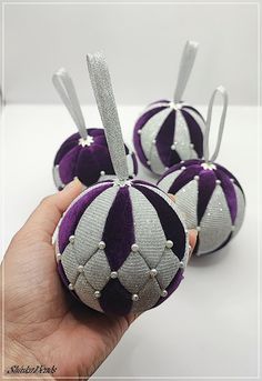 three purple and silver ornaments in the shape of balls