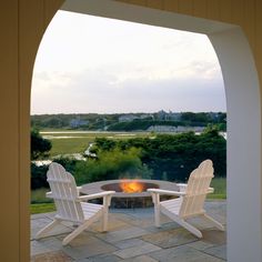 two white chairs sitting around a fire pit