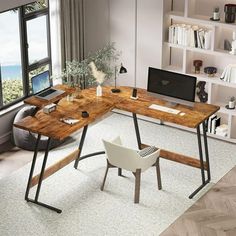 a computer desk sitting in front of a window next to a chair and book shelf